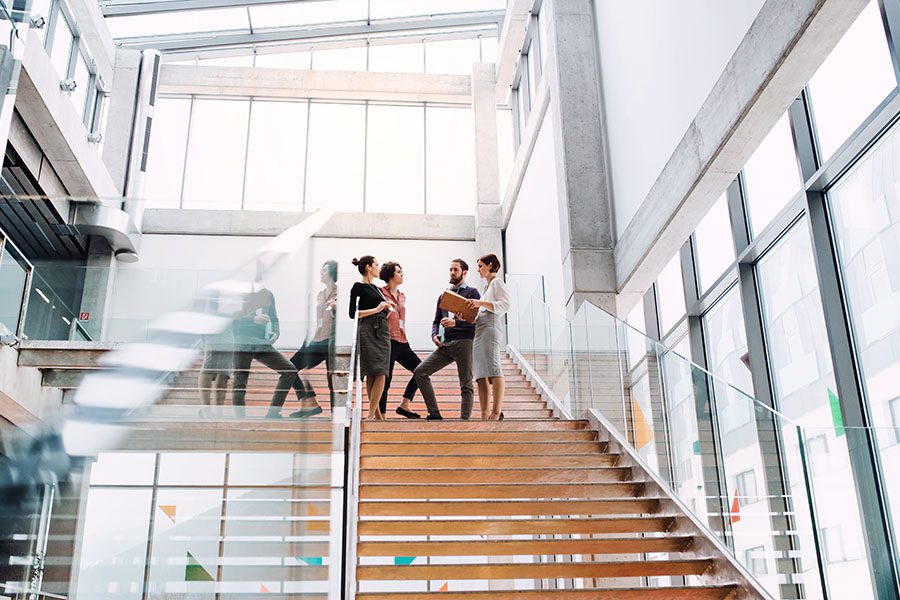 Business Insurance - View of Group of Coworkers Standing on the Stairs Talking in a Modern Office