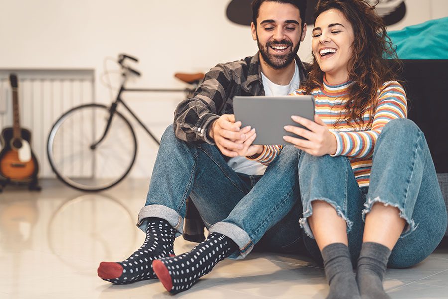 Client Center - Young Smiling Couple Sitting on the Floor in Their Apartment Using a Tablet Together