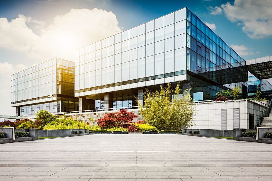 Specialized Business Insurance - View of a Modern Glass Office Building Against Blue Sky with Green Landscaping in the Front